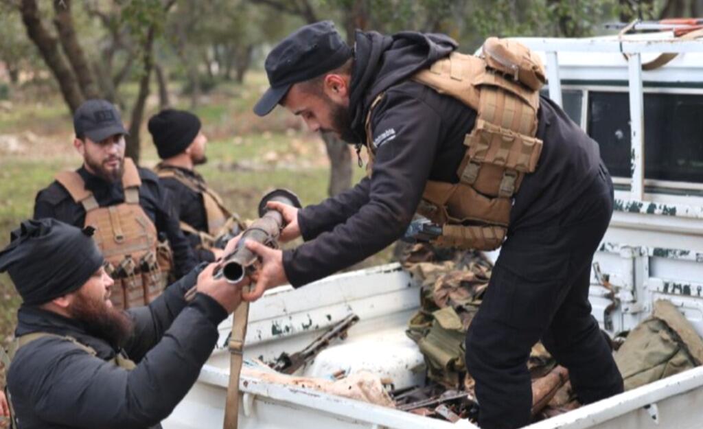 Syrian internal security personnel handling seized weapons in a pickup truck in the Masyaf area, western Hama.